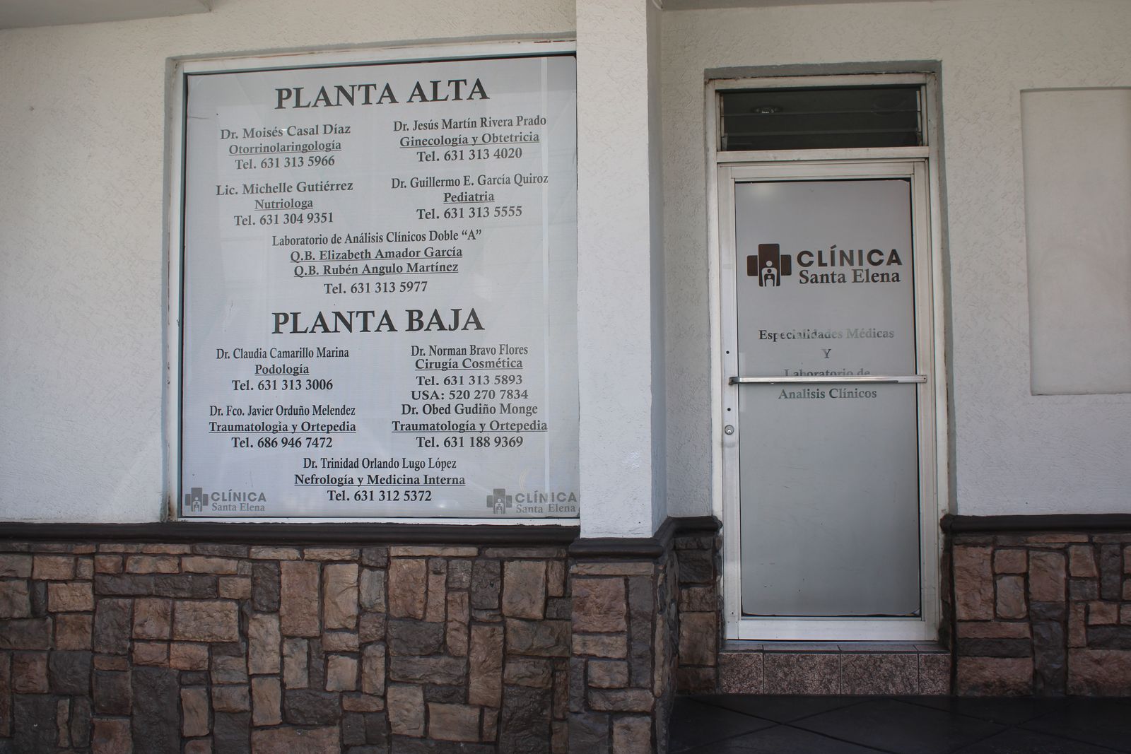 Ventana con el directorio de Clínica Santa Elena, donde el Dr. Moisés Casal Díaz aparece en Planta Alta, junto a la puerta de cristal de la clínica