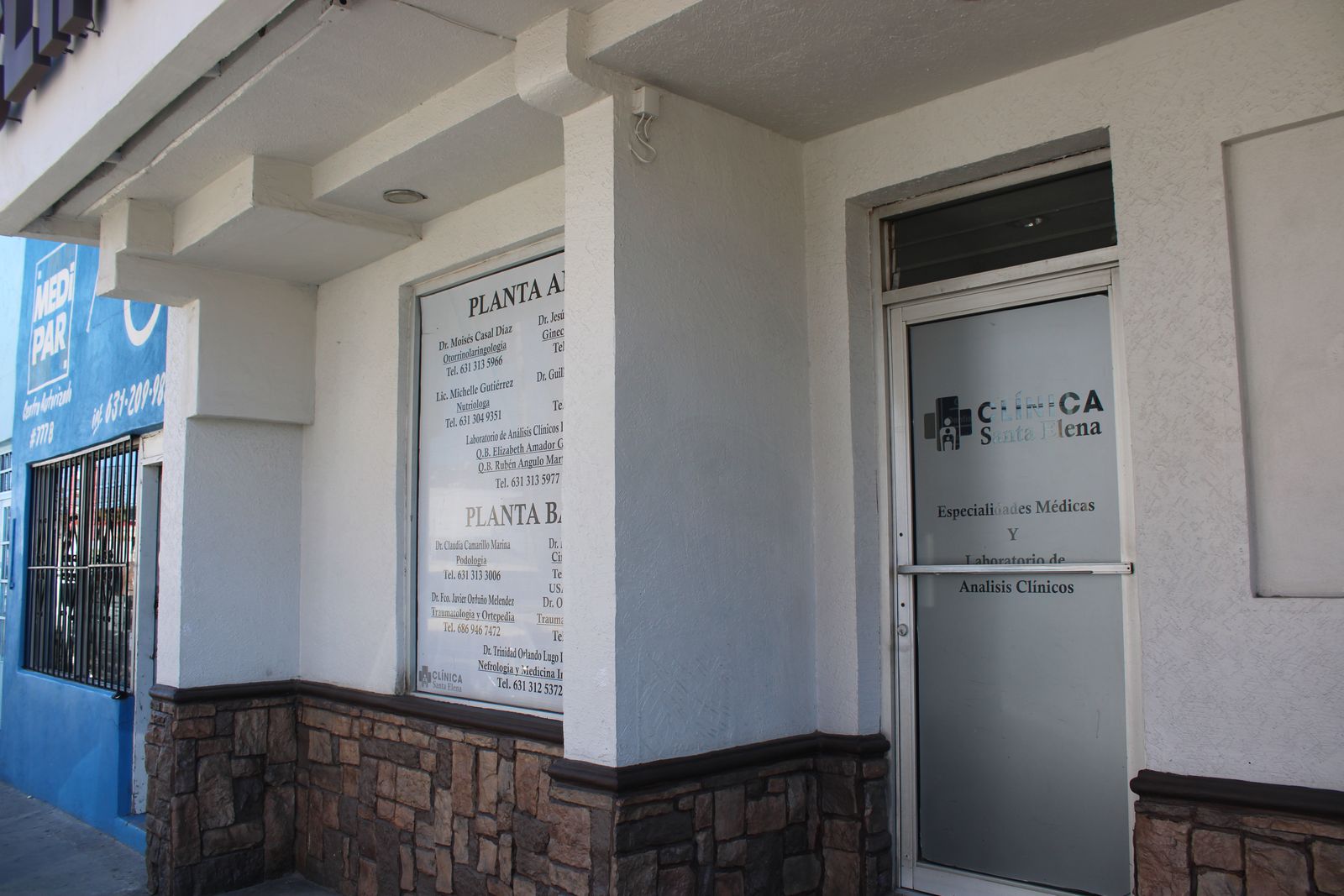 La entrada de Clínica Santa Elena vista desde la banqueta: el directorio y la puerta de cristal con el logo de la clínica
