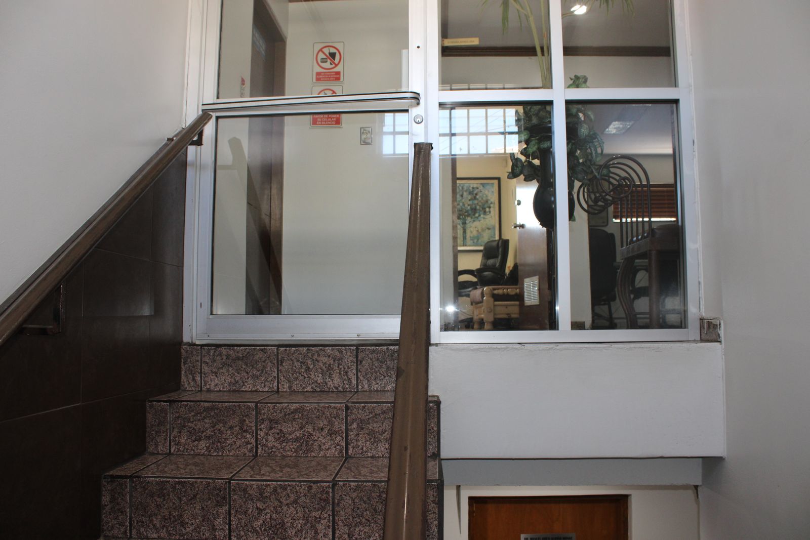 Escalera de Clínica Santa Elena que sube hasta la puerta de cristal de Planta Alta