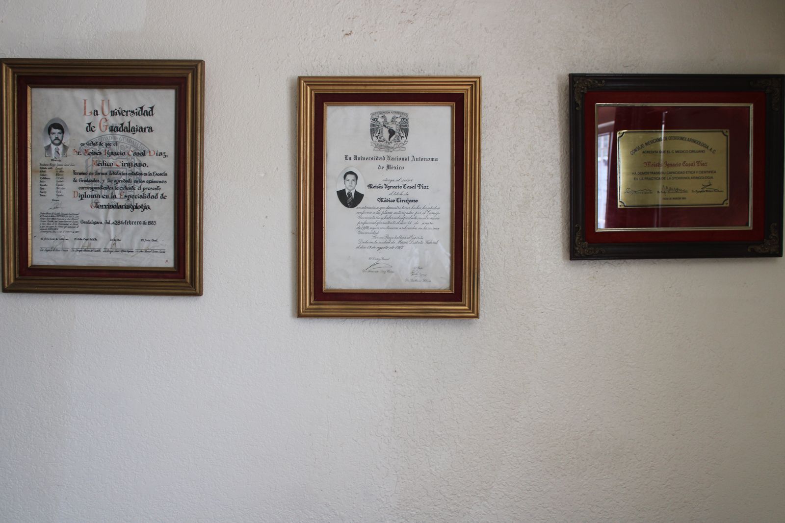 Pared del consultorio con tres diplomas enmarcados del Dr. Casal